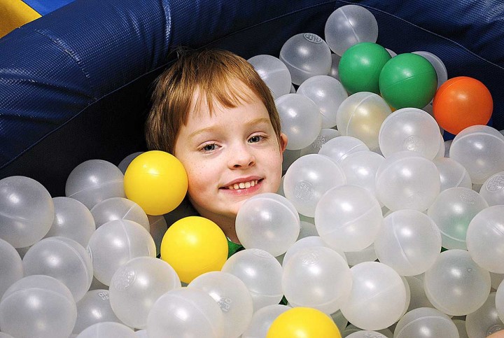 A boy smiles in a ball pit