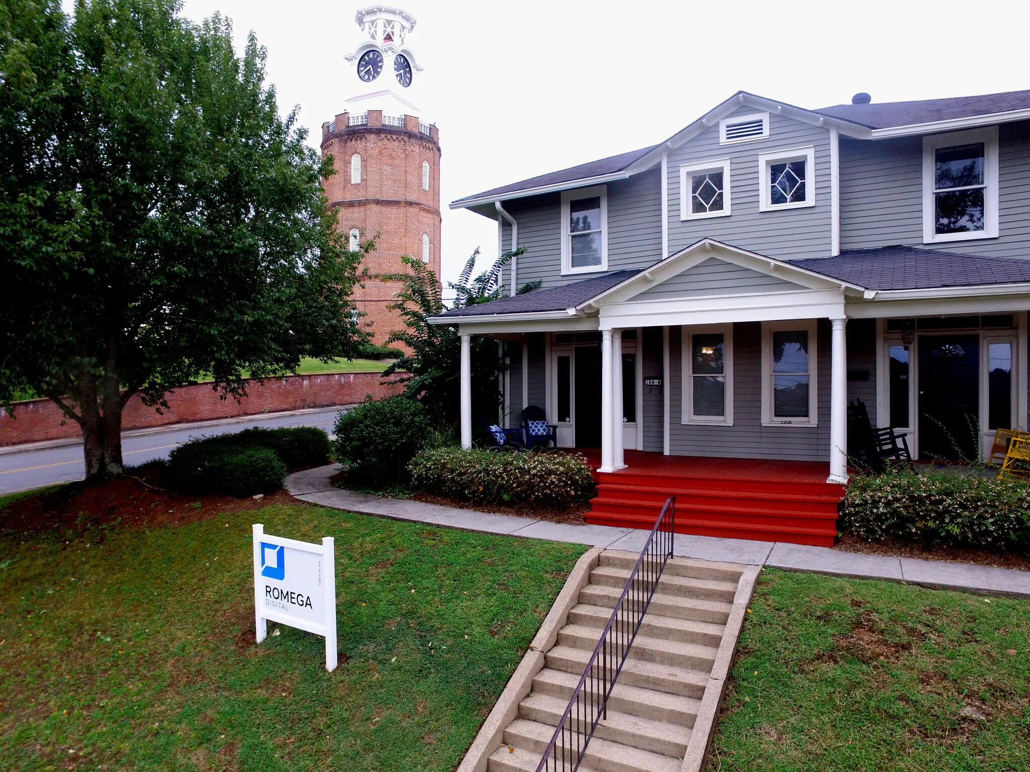 A blue house near a clocktower. A sign says Romega Digital.