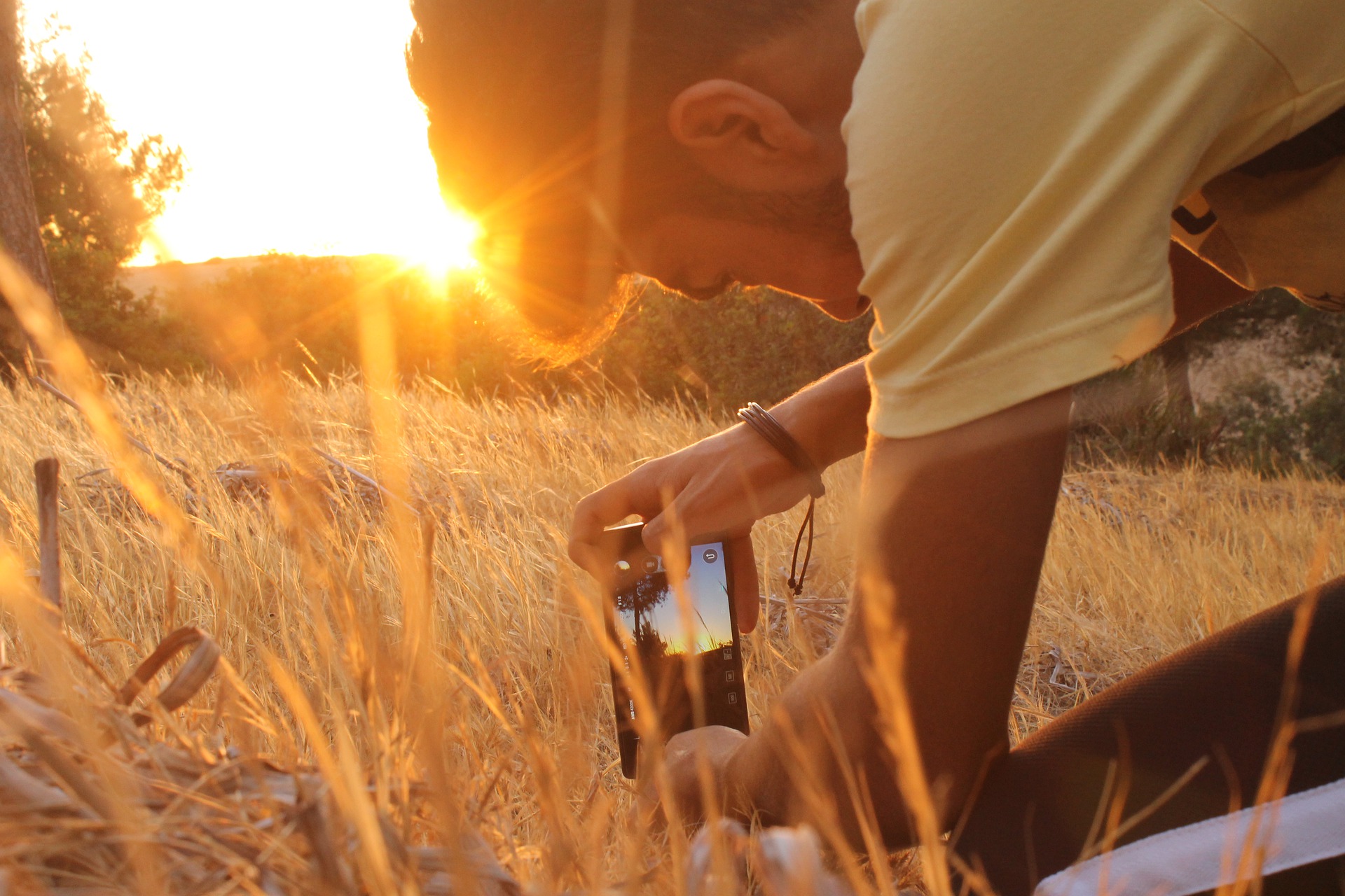 A man uses his phone to shoot a video in a field